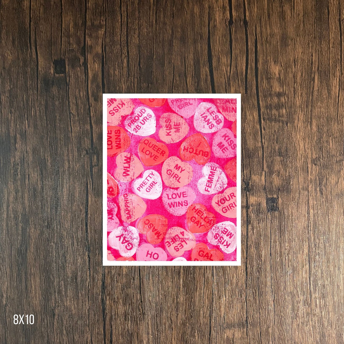 Poster with pink and red heart-shaped conversation pieces on a wooden surface