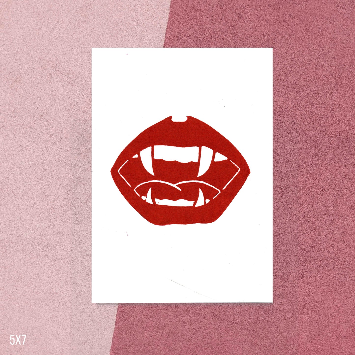 Red lips and vampire fangs graphic on white paper against a pink background
