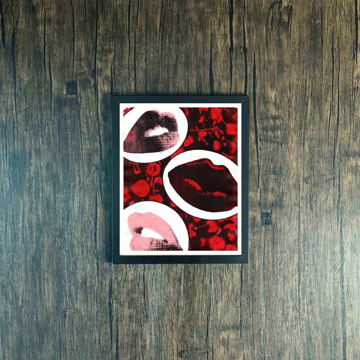 Framed Poster with red and black abstract design of lips and cherries on a wooden surface