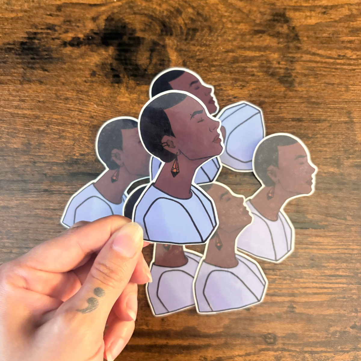 Sticker of woman with buzzcut and sunset earrings.
