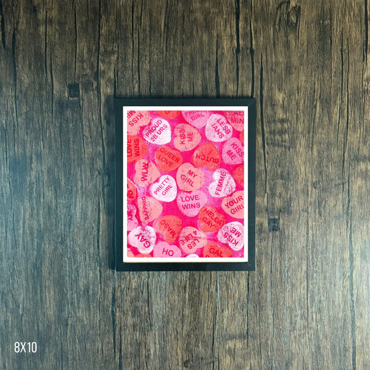 Framed artwork with pink and red text heart pattern on a wooden surface