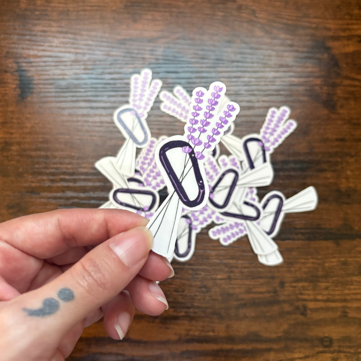 Sticker of carabiner with lavender flowers looped through the middle.